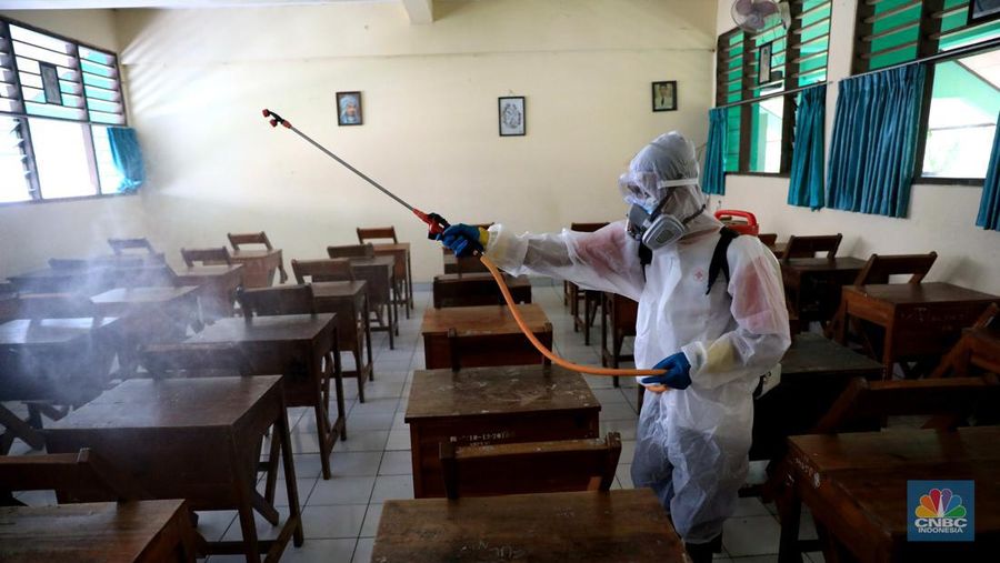 Petugas PMI menyemprotkan disinfektan di salah satu ruang kelas di SMPN 97, Jakarta, Kamis (3/2/2022). (CNBC Indonesia/Muhammad Sabki)