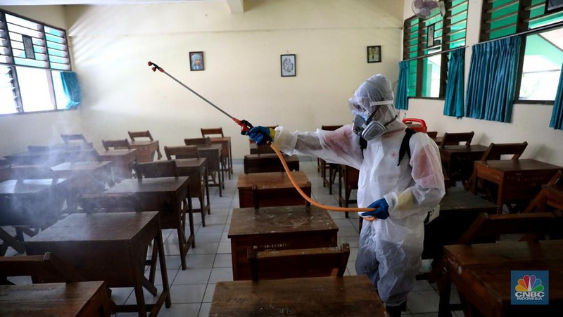 Petugas PMI menyemprotkan disinfektan di salah satu ruang kelas di SMPN 97, Jakarta, Kamis (3/2/2022). (CNBC Indonesia/Muhammad Sabki)