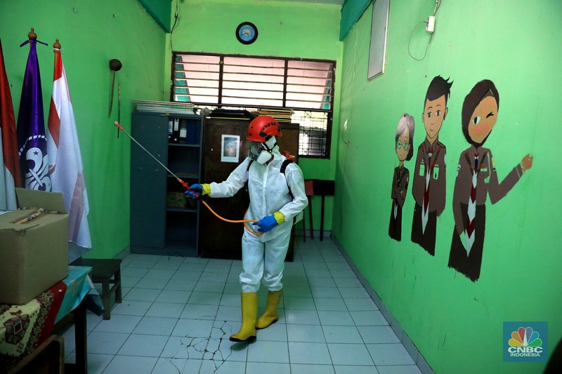 Petugas PMI menyemprotkan disinfektan di salah satu ruang kelas di SMPN 97, Jakarta, Kamis (3/2/2022). (CNBC Indonesia/Muhammad Sabki)