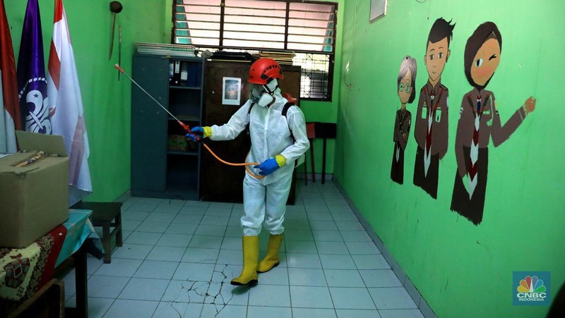 Petugas PMI menyemprotkan disinfektan di salah satu ruang kelas di SMPN 97, Jakarta, Kamis (3/2/2022). (CNBC Indonesia/Muhammad Sabki)