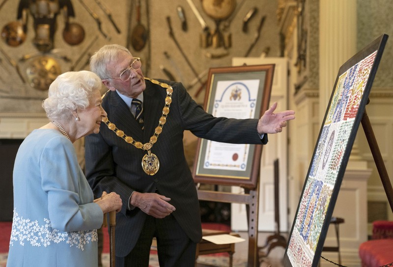 CORRECTION Britain Queen Platinum Jubilee Britain's Queen Elizabeth II looks at a display of memorabilia from her Golden and Platinum Jubilees in the Oak Room at Windsor Castle, Windsor, England, in this undated but recent image that was released on Friday Feb. 4, 2022. Queen Elizabeth II will mark 70 years on the throne Sunday Feb. 6, an unprecedented reign that has made her a symbol of stability as the United Kingdom navigated an age of uncertainty. (Steve Parsons/Pool via AP)