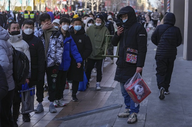 A man holds the Olympic mascot Bing Dwen Dwen doll which he purchased form a store selling 2022 Winter Olympics memorabilia in Beijing, Monday, Feb. 7, 2022. The race is on to snap up scarce 2022 Winter Olympics souvenirs. Dolls of mascot Bing Dwen Dwen, a panda in a winter coat, sold out after buyers waited in line overnight in freezing weather. (AP Photo/Andy Wong)