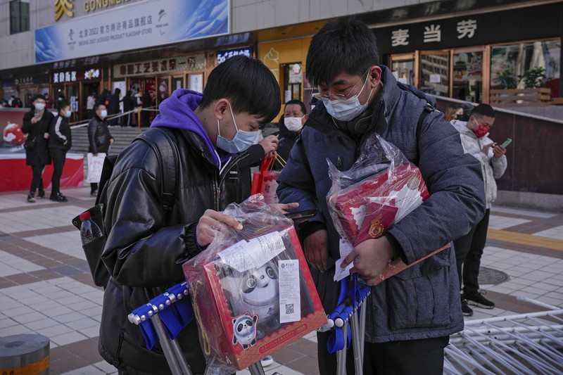 A man holds the Olympic mascot Bing Dwen Dwen doll which he purchased form a store selling 2022 Winter Olympics memorabilia in Beijing, Monday, Feb. 7, 2022. The race is on to snap up scarce 2022 Winter Olympics souvenirs. Dolls of mascot Bing Dwen Dwen, a panda in a winter coat, sold out after buyers waited in line overnight in freezing weather. (AP Photo/Andy Wong)