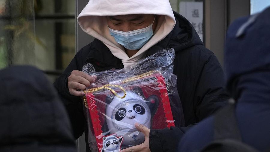 A man holds the Olympic mascot Bing Dwen Dwen doll which he purchased form a store selling 2022 Winter Olympics memorabilia in Beijing, Monday, Feb. 7, 2022. The race is on to snap up scarce 2022 Winter Olympics souvenirs. Dolls of mascot Bing Dwen Dwen, a panda in a winter coat, sold out after buyers waited in line overnight in freezing weather. (AP Photo/Andy Wong)