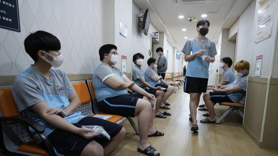 People wait for their coronavirus test at a makeshift testing site in Seoul, South Korea, Monday, Feb. 7, 2022. South Korea will no longer use GPS monitoring to enforce quarantines and will also end daily checkup calls to low-risk coronavirus patients as a fast-developing omicron surge overwhelms health and government workers. (AP Photo/Ahn Young-joon)