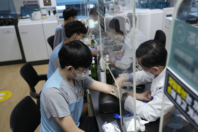 Virus Outbreak South Korea People wait for their coronavirus test at a makeshift testing site in Seoul, South Korea, Monday, Feb. 7, 2022. South Korea will no longer use GPS monitoring to enforce quarantines and will also end daily checkup calls to low-risk coronavirus patients as a fast-developing omicron surge overwhelms health and government workers. (AP Photo/Ahn Young-joon)