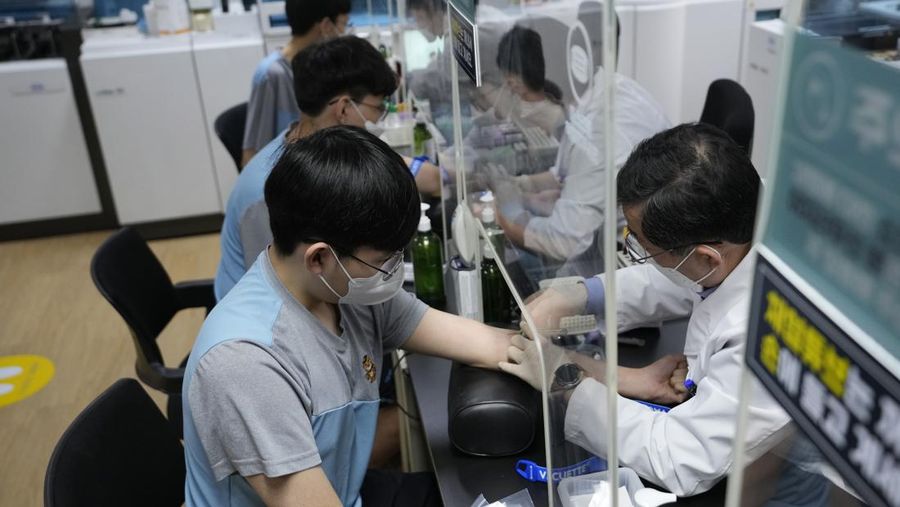 South Korean prospective soldiers wearing face masks have their blood taken during a medical checkup at the Seoul office of the Military Manpower Administration in Seoul, South Korea, Monday, Feb. 7, 2022. (AP Photo/Ahn Young-joon)