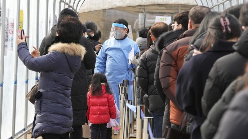 People wait for their coronavirus test at a makeshift testing site in Seoul, South Korea, Monday, Feb. 7, 2022. South Korea will no longer use GPS monitoring to enforce quarantines and will also end daily checkup calls to low-risk coronavirus patients as a fast-developing omicron surge overwhelms health and government workers. (AP Photo/Ahn Young-joon)