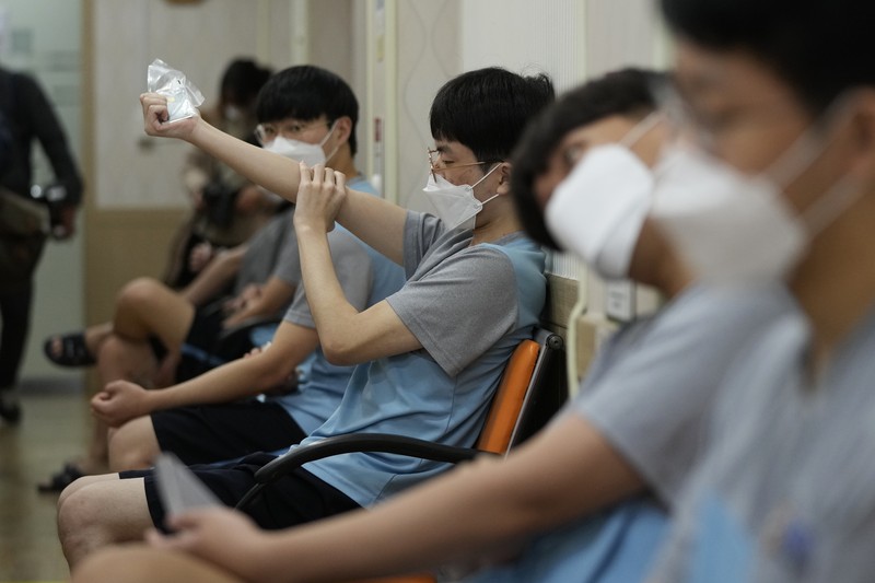 Virus Outbreak South Korea People wait for their coronavirus test at a makeshift testing site in Seoul, South Korea, Monday, Feb. 7, 2022. South Korea will no longer use GPS monitoring to enforce quarantines and will also end daily checkup calls to low-risk coronavirus patients as a fast-developing omicron surge overwhelms health and government workers. (AP Photo/Ahn Young-joon)
