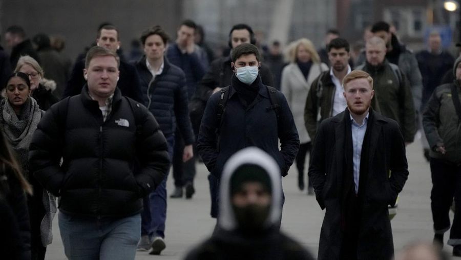 Workers walk over London Bridge towards the City of London financial district during the morning rush hour, in London, Monday, Jan. 24, 2022. The British government have asked people to return to working in offices starting Monday as they ease coronavirus restrictions. (AP Photo/Matt Dunham)