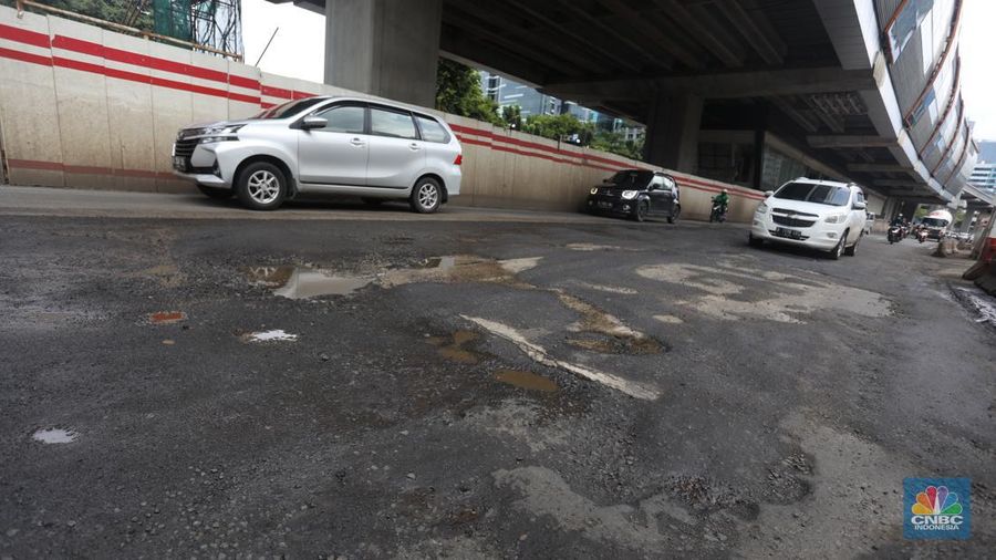 Kendaraan melintasi jalan yang rusak di kawasan H. R. Rasuna Said, Jakarta, Rabu (9/2/2022). Jalan rusak ini sangat berbahaga bagi pengendara terlebih saat hujan turun. (CNBC Indonesia/Andrean Kristianto)