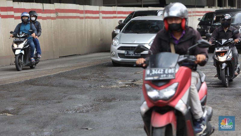 Kendaraan melintasi jalan yang rusak di kawasan H. R. Rasuna Said, Jakarta, Rabu (9/2/2022). Jalan rusak ini sangat berbahaga bagi pengendara terlebih saat hujan turun. (CNBC Indonesia/Andrean Kristianto)