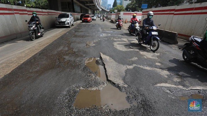 Kendaraan melintasi jalan yang rusak di kawasan H. R. Rasuna Said, Jakarta, Rabu (9/2/2022). Jalan rusak ini sangat berbahaga bagi pengendara terlebih saat hujan turun. (CNBC Indonesia/Andrean Kristianto)