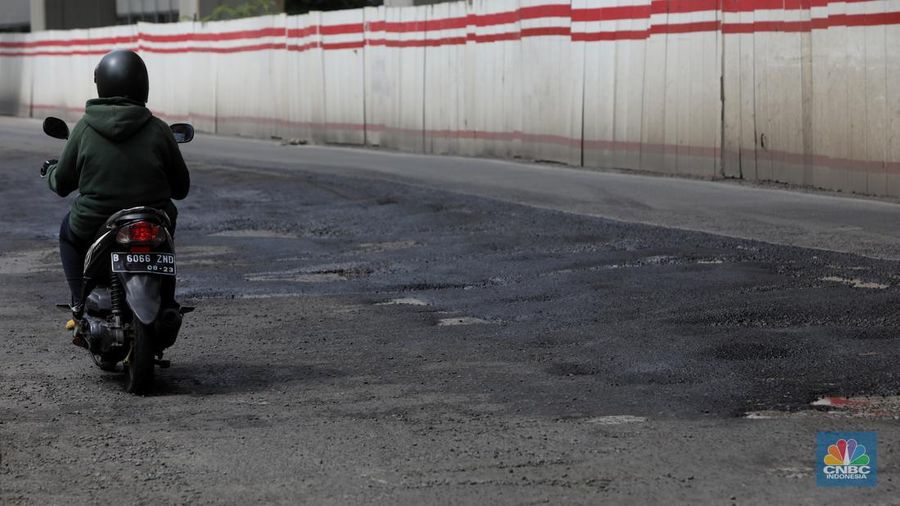 Kendaraan melintasi jalan yang rusak di kawasan H. R. Rasuna Said, Jakarta, Rabu (9/2/2022). Jalan rusak ini sangat berbahaga bagi pengendara terlebih saat hujan turun. (CNBC Indonesia/Andrean Kristianto)