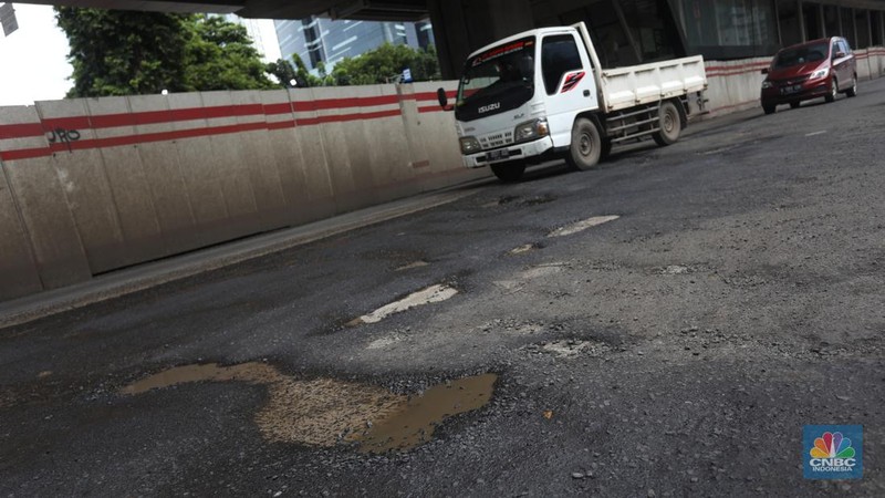 Kendaraan melintasi jalan yang rusak di kawasan H. R. Rasuna Said, Jakarta, Rabu (9/2/2022). Jalan rusak ini sangat berbahaga bagi pengendara terlebih saat hujan turun. (CNBC Indonesia/Andrean Kristianto)