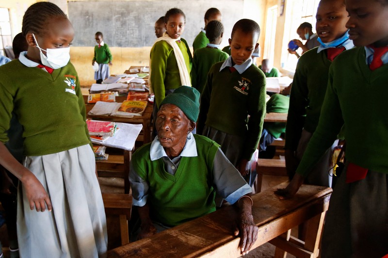 KENYA-EDUCATION/GRANDMA Priscilla Sitienei, a 98-year-old primary school student in grade six, is helped to do an assignment by her classmate at the Leaders Vision Preparatory School in Ndalat village of Nandi County, Kenya January 25, 2022. Picture taken January 25, 2022. REUTERS/Monicah Mwangi