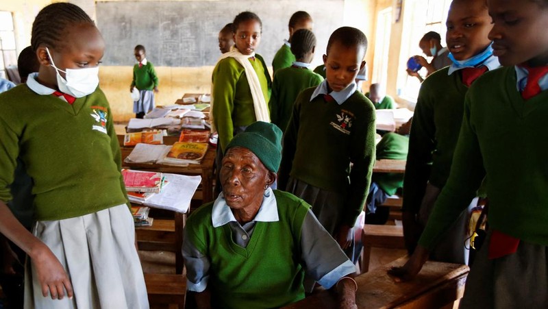 Priscilla Sitienei, a 98-year-old primary school student in grade six, is helped to do an assignment by her classmate at the Leaders Vision Preparatory School in Ndalat village of Nandi County, Kenya January 25, 2022. Picture taken January 25, 2022. REUTERS/Monicah Mwangi