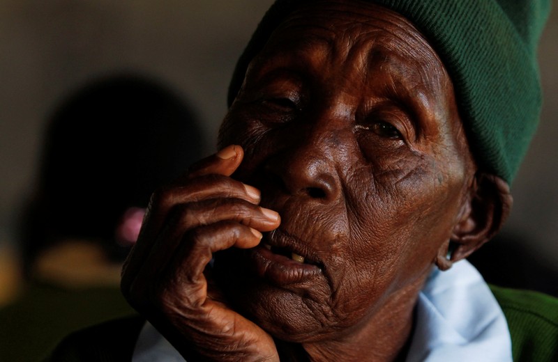 KENYA-EDUCATION/GRANDMA Priscilla Sitienei, a 98-year-old primary school student in grade six, is helped to do an assignment by her classmate at the Leaders Vision Preparatory School in Ndalat village of Nandi County, Kenya January 25, 2022. Picture taken January 25, 2022. REUTERS/Monicah Mwangi