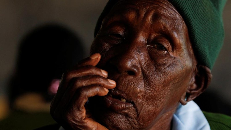 Priscilla Sitienei, a 98-year-old primary school student in grade six, is helped to do an assignment by her classmate at the Leaders Vision Preparatory School in Ndalat village of Nandi County, Kenya January 25, 2022. Picture taken January 25, 2022. REUTERS/Monicah Mwangi
