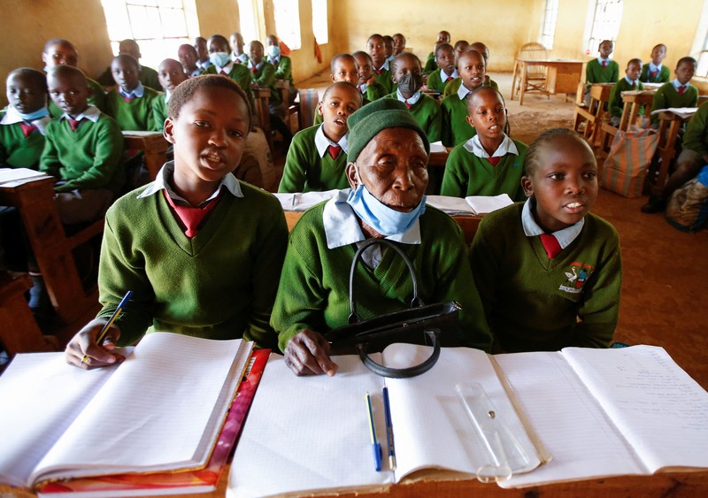 KENYA-EDUCATION/GRANDMA Priscilla Sitienei, a 98-year-old primary school student in grade six, is helped to do an assignment by her classmate at the Leaders Vision Preparatory School in Ndalat village of Nandi County, Kenya January 25, 2022. Picture taken January 25, 2022. REUTERS/Monicah Mwangi