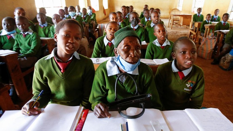 Priscilla Sitienei, a 98-year-old primary school student in grade six, is helped to do an assignment by her classmate at the Leaders Vision Preparatory School in Ndalat village of Nandi County, Kenya January 25, 2022. Picture taken January 25, 2022. REUTERS/Monicah Mwangi