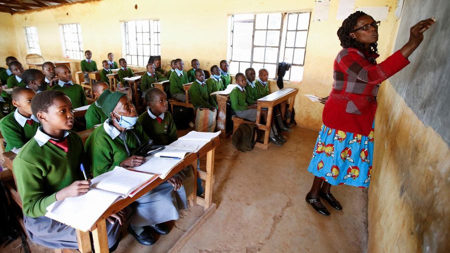 Priscilla Sitienei, a 98-year-old primary school student in grade six, is helped to do an assignment by her classmate at the Leaders Vision Preparatory School in Ndalat village of Nandi County, Kenya January 25, 2022. Picture taken January 25, 2022. REUTERS/Monicah Mwangi