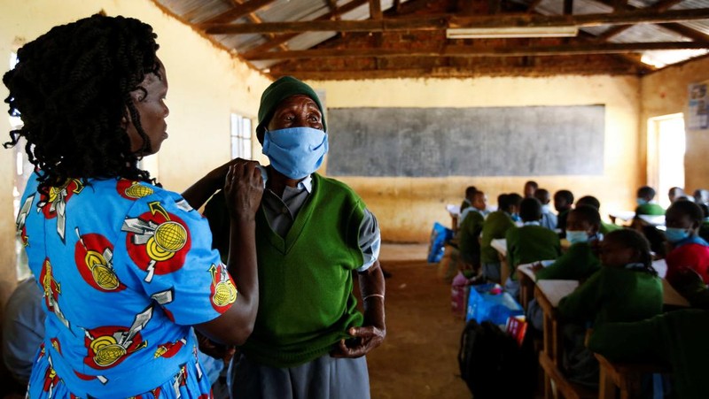 Priscilla Sitienei, a 98-year-old primary school student in grade six, is helped to do an assignment by her classmate at the Leaders Vision Preparatory School in Ndalat village of Nandi County, Kenya January 25, 2022. Picture taken January 25, 2022. REUTERS/Monicah Mwangi