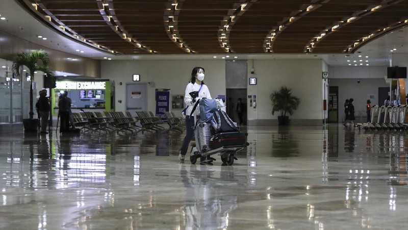 Airport officials check documents of foreign passengers at a counter as they arrive at Manila's International Airport, Philippines Thursday, Feb. 10, 2022. The Philippines lifted a nearly 2-year ban on foreign travelers Thursday in a lifesaving boost for its tourism and related industries as an omicron-fueled surge eases. (AP Photo/Basilio Sepe)