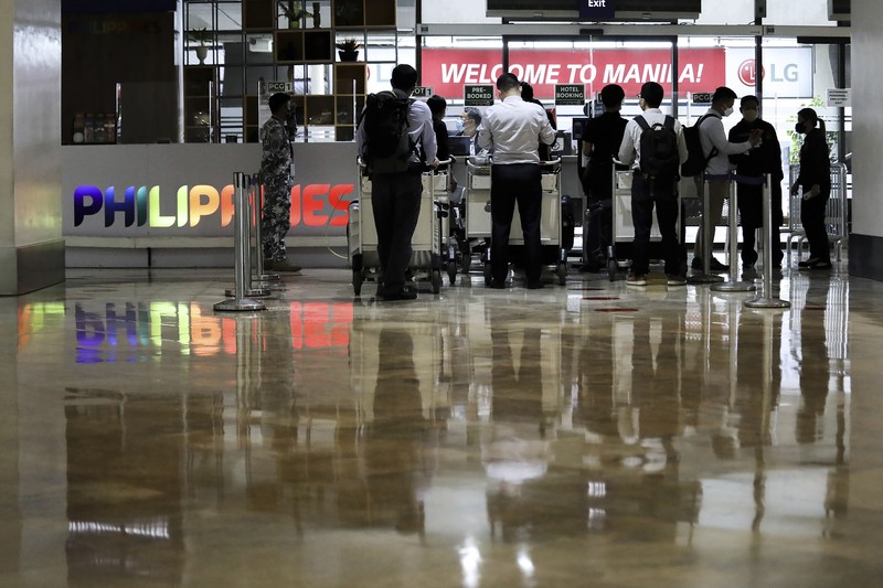 Virus Outbreak Philippines Airport officials check documents of foreign passengers at a counter as they arrive at Manila's International Airport, Philippines Thursday, Feb. 10, 2022. The Philippines lifted a nearly 2-year ban on foreign travelers Thursday in a lifesaving boost for its tourism and related industries as an omicron-fueled surge eases. (AP Photo/Basilio Sepe)