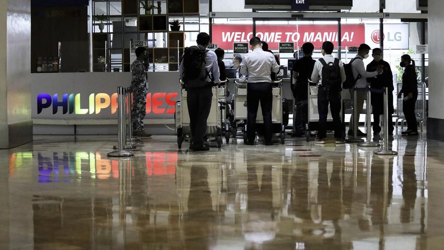 Airport officials check documents of foreign passengers at a counter as they arrive at Manila's International Airport, Philippines Thursday, Feb. 10, 2022. The Philippines lifted a nearly 2-year ban on foreign travelers Thursday in a lifesaving boost for its tourism and related industries as an omicron-fueled surge eases. (AP Photo/Basilio Sepe)