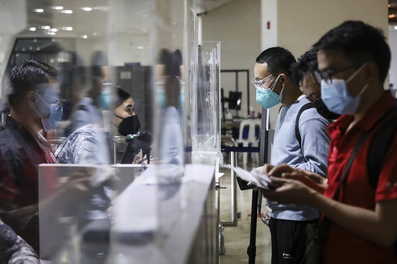Virus Outbreak Philippines Airport officials check documents of foreign passengers at a counter as they arrive at Manila's International Airport, Philippines Thursday, Feb. 10, 2022. The Philippines lifted a nearly 2-year ban on foreign travelers Thursday in a lifesaving boost for its tourism and related industries as an omicron-fueled surge eases. (AP Photo/Basilio Sepe)