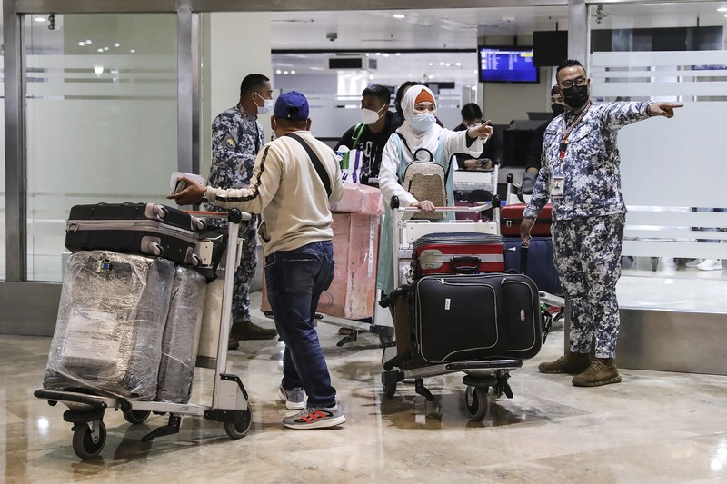 Virus Outbreak Philippines Airport officials check documents of foreign passengers at a counter as they arrive at Manila's International Airport, Philippines Thursday, Feb. 10, 2022. The Philippines lifted a nearly 2-year ban on foreign travelers Thursday in a lifesaving boost for its tourism and related industries as an omicron-fueled surge eases. (AP Photo/Basilio Sepe)