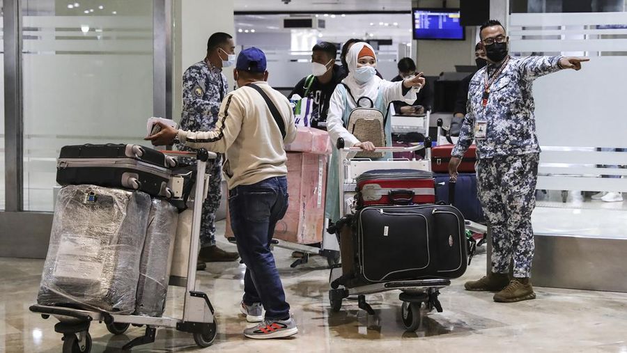 Airport officials check documents of foreign passengers at a counter as they arrive at Manila's International Airport, Philippines Thursday, Feb. 10, 2022. The Philippines lifted a nearly 2-year ban on foreign travelers Thursday in a lifesaving boost for its tourism and related industries as an omicron-fueled surge eases. (AP Photo/Basilio Sepe)