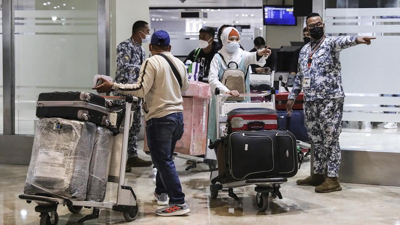 Airport officials check documents of foreign passengers at a counter as they arrive at Manila's International Airport, Philippines Thursday, Feb. 10, 2022. The Philippines lifted a nearly 2-year ban on foreign travelers Thursday in a lifesaving boost for its tourism and related industries as an omicron-fueled surge eases. (AP Photo/Basilio Sepe)