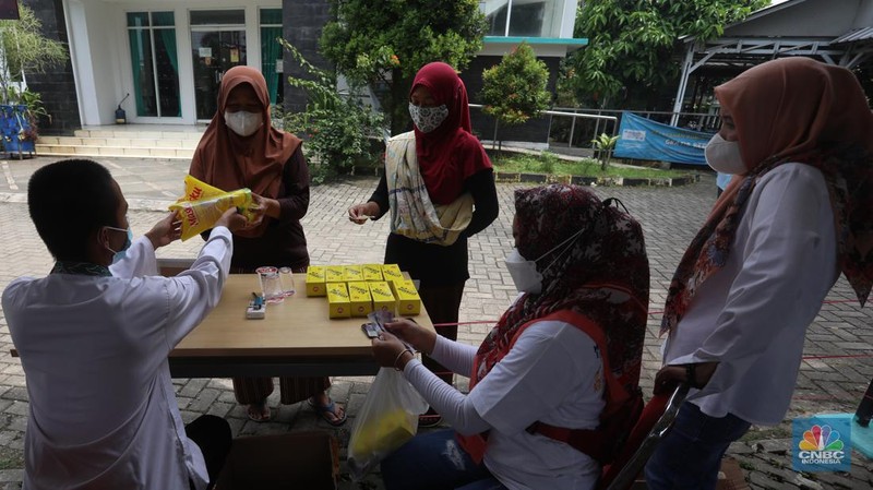 Warga menukarkan kupon untuk membeli minyak goreng saat pasar murah di Kantor Kelurahan Lenkong Karya, Serpong, Tangerang Selatan, Jumat (11/2/2022). (CNBC Indonesia/Andrean Kristianto)