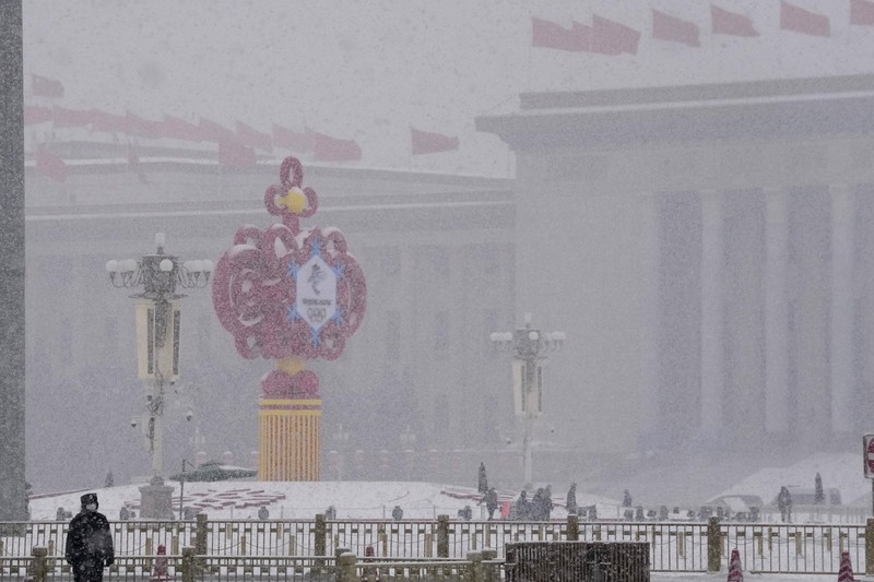 Seorang pria berlari saat salju turun di Beijing, Minggu (13/2/2022). (AP Photo/Mark Baker)