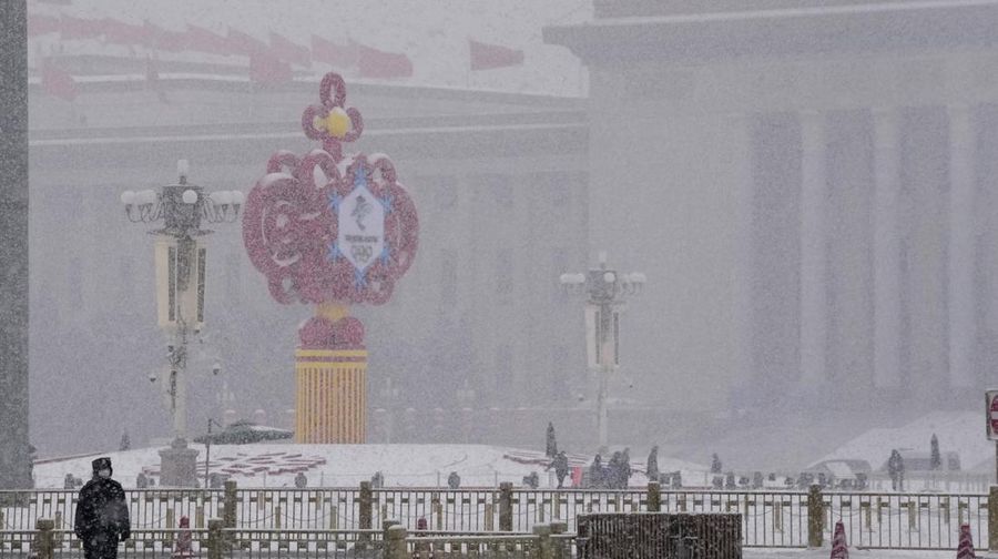Seorang pria berlari saat salju turun di Beijing, Minggu (13/2/2022). (AP Photo/Mark Baker)