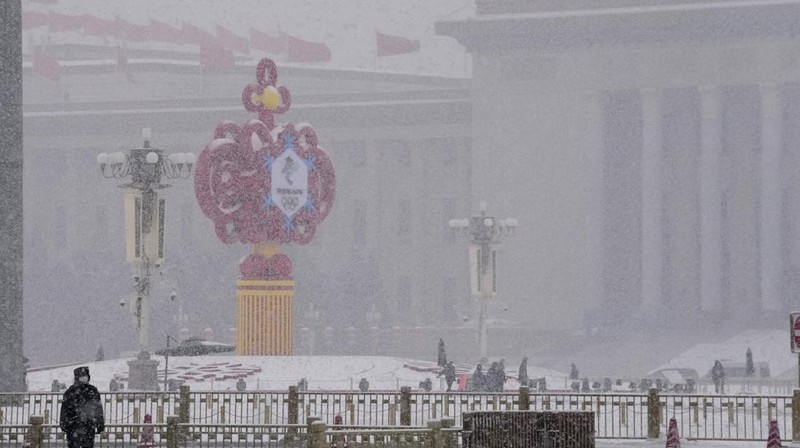 Seorang pria berlari saat salju turun di Beijing, Minggu (13/2/2022). (AP Photo/Mark Baker)