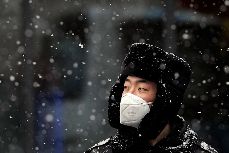 Seorang pria berlari saat salju turun di Beijing, Minggu (13/2/2022). (AP Photo/Mark Baker)