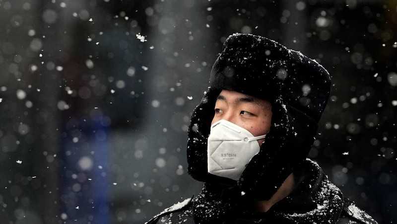 Seorang pria berlari saat salju turun di Beijing, Minggu (13/2/2022). (AP Photo/Mark Baker)