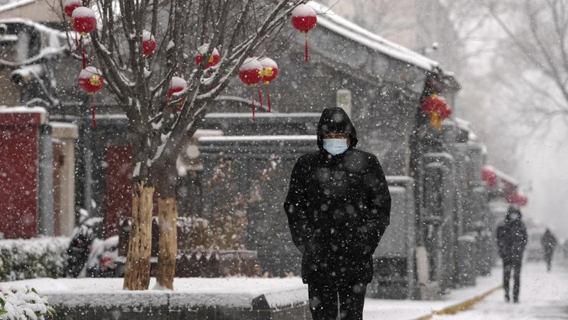 Seorang pria berlari saat salju turun di Beijing, Minggu (13/2/2022). (AP Photo/Mark Baker)