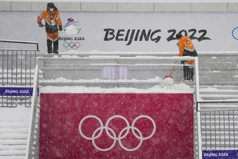 Seorang pria berlari saat salju turun di Beijing, Minggu (13/2/2022). (AP Photo/Mark Baker)