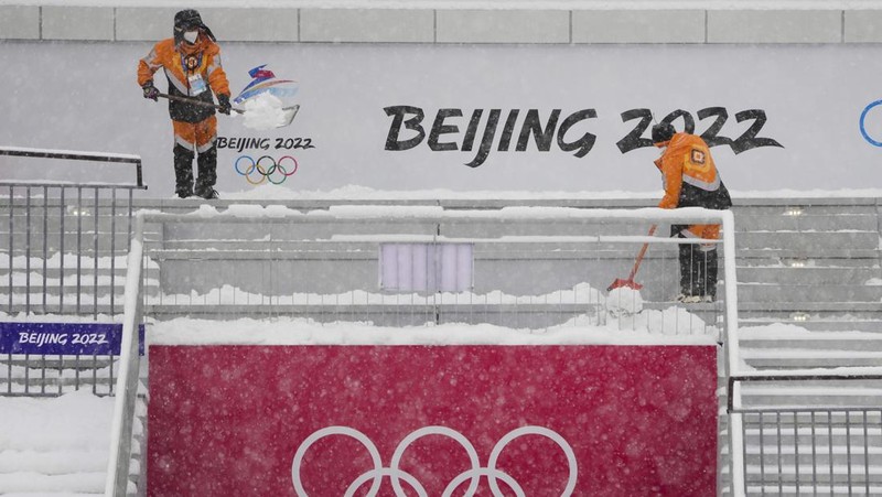Seorang pria berlari saat salju turun di Beijing, Minggu (13/2/2022). (AP Photo/Mark Baker)