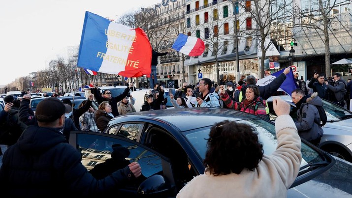 Para pengunjuk rasa mengibarkan bendera Prancis di jalan Champs-Elysees saat mobil berparade selama 