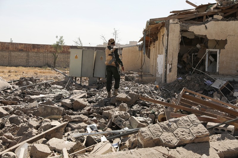 Seorang penjaga keamanan memeriksa lokasi serangan udara koalisi militer pimpinan Arab Saudi di sebuah stasiun telekomunikasi di Sanaa, Yaman, Senin (14/2/2022). (REUTERS/Khaled Abdullah)
