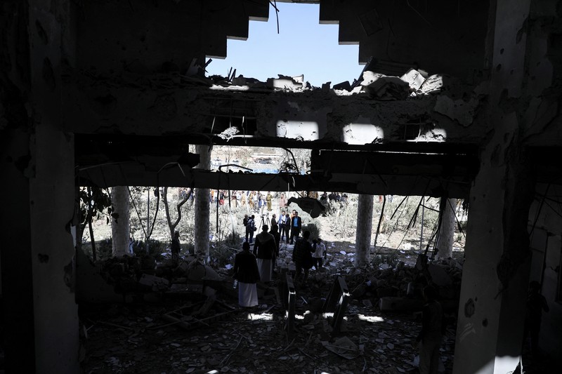 Seorang penjaga keamanan memeriksa lokasi serangan udara koalisi militer pimpinan Arab Saudi di sebuah stasiun telekomunikasi di Sanaa, Yaman, Senin (14/2/2022). (REUTERS/Khaled Abdullah)