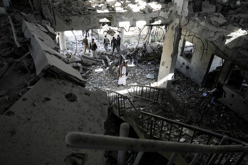 Seorang penjaga keamanan memeriksa lokasi serangan udara koalisi militer pimpinan Arab Saudi di sebuah stasiun telekomunikasi di Sanaa, Yaman, Senin (14/2/2022). (REUTERS/Khaled Abdullah)