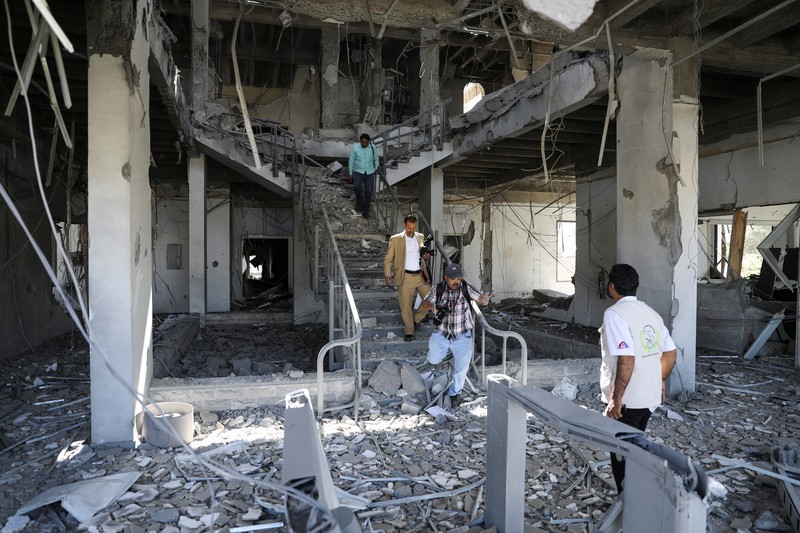 Seorang penjaga keamanan memeriksa lokasi serangan udara koalisi militer pimpinan Arab Saudi di sebuah stasiun telekomunikasi di Sanaa, Yaman, Senin (14/2/2022). (REUTERS/Khaled Abdullah)