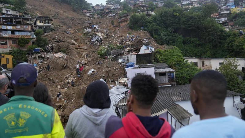 Rescue workers and residents search for victims in an area affected by landslides in Petropolis, Brazil, Wednesday, Feb. 16, 2022. Extremely heavy rains set off mudslides and floods in a mountainous region of Rio de Janeiro state, killing multiple people, authorities reported. (AP Photo/Silvia Izquierdo)