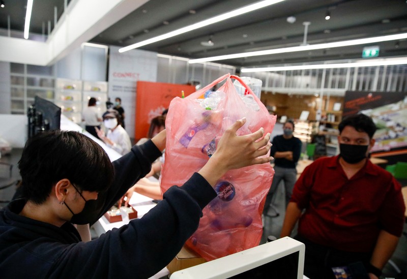 THAILAND-ENVIRONMENT/PLASTIC-AMULETS A woman shows an amulet, above 1kg of plastic bottles, which was made from 1kg of trash such as plastic bags, bottle caps, milk cotton and fishing nets, at Bangkok Design Week festival, in Bangkok, Thailand January 12, 2022. Picture taken January 12, 2022. REUTERS/Soe Zeya Tun